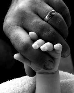 A father's hand holding a baby's hand