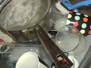 A picture of some dishes in a sink full of soapy water