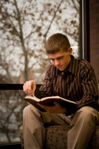 A picture of a young man reading his scriptures